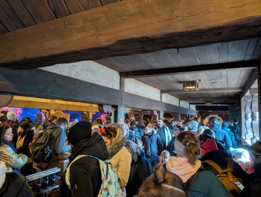 A crowded queue line inside the Les Voyages de Pinocchio ride, with many people waiting, illustrating the reality of theme park wait times.