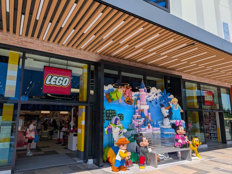 The entrance of the LEGO Store in Disneyland Paris's Disney Village, featuring large LEGO statues of Disney characters like Mickey Mouse, Minnie Mouse, Woody, and Elsa.