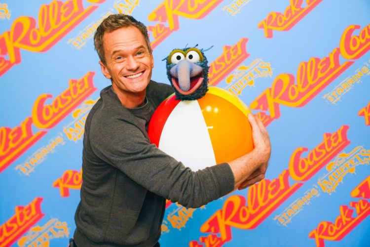 A smiling Neil Patrick Harris hugging a Gonzo the Great puppet and a beach ball against a blue background with the "Rock 'n' Roller Coaster Starring The Muppets" logo.
