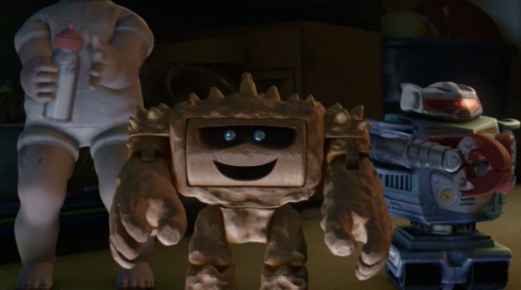 Chunk, the rock-like monster toy from Toy Story 3, smiling with bright blue eyes alongside other henchmen toys at Sunnyside Daycare.