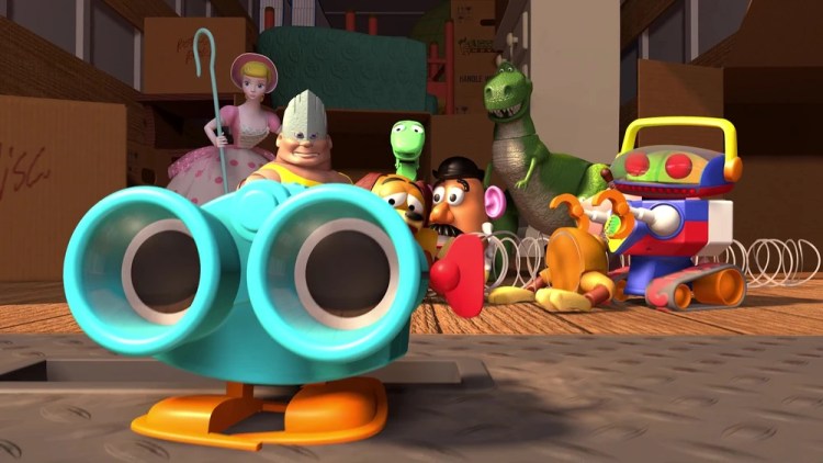 Lenny the blue wind-up binoculars toy standing in the foreground, with Woody, Bo Peep, Rex, Slinky, and Mr. Potato Head gathered behind him inside a moving box.